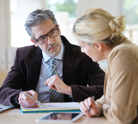 What You Get With Always Synergy's Security Risk Consulting Business professional reviewing documents and explaining details to a colleague across a desk in an office setting.